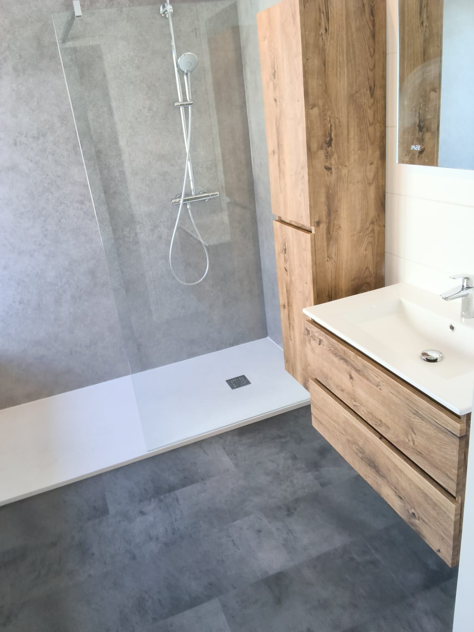 Moderne badkamer met inloopdouche, houtlook wastafelmeubel en grijze wandpanelen.