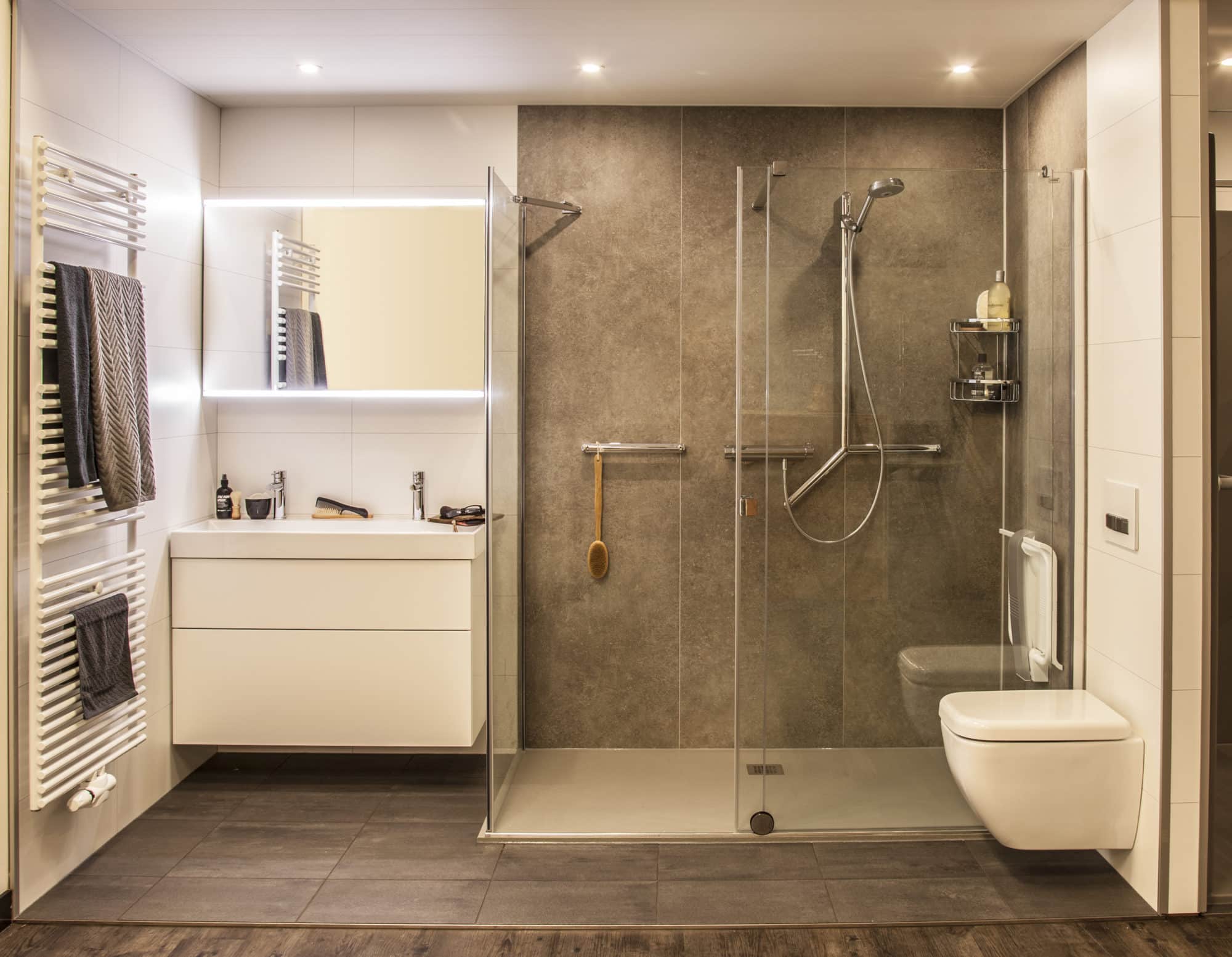 Moderne badkamer met inloopdouche, wandcloset en wastafelmeubel in grijstinten.